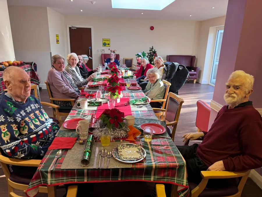 Residents sitting down to Christmas dinner at a long, decorated table