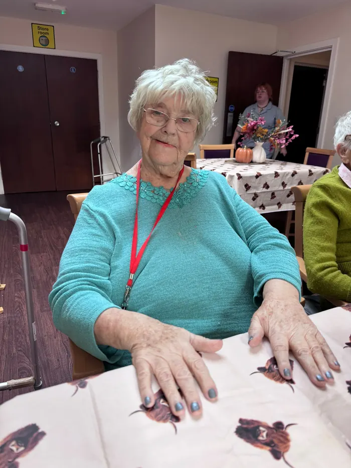A resident smiling at the table, showing her freshly painted nails